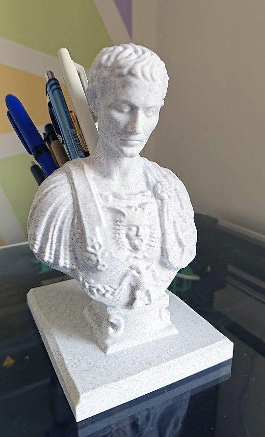 Slika prikazuje 3d printani mramorni bust Julije Cezara koji služi kao držač za olovke na leđima.